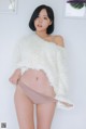 a woman in a white sweater and panties posing for a picture