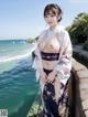 A woman in a kimono posing by the water.