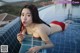 A woman in a red bikini laying on the edge of a swimming pool.