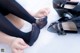 A woman is putting on a pair of black shoes.