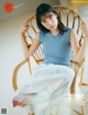 A woman sitting in a wicker chair wearing a blue top and white skirt.