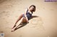 A woman in a bathing suit laying on the sand.