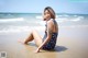 A woman sitting on the beach in a bathing suit.