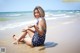 A woman sitting on the beach in a bathing suit.