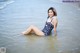 A woman in a bathing suit sitting in the water.