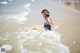 A woman in a bathing suit sitting in the ocean.