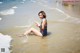 A woman sitting in the water at the beach.