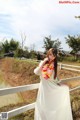 A woman in a white dress standing on a white fence.