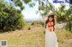 A woman in a white dress standing under a tree.