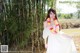 A woman in a white dress standing in front of a bamboo forest.