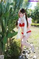 A woman in a red bikini posing next to a cactus.