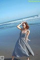 A woman in a black and white dress standing on a beach.