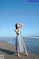 A woman standing on a beach next to the ocean.