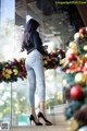 A woman standing in front of a Christmas tree looking at her phone.