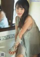 A woman sitting on a bathtub in front of a mirror.