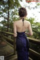 A woman in a blue dress standing on a wooden bridge.