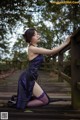 A woman in a purple dress sitting on a wooden bridge.