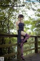 A woman in a black dress and purple stockings posing on a wooden bridge.