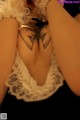 A woman with a tattoo on her back is posing for the camera.