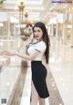 A woman in a white shirt and black skirt standing in a mall.