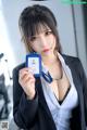 A woman in a business suit holding up a blue id card.