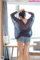 a woman in shorts and a sweater standing in front of a window