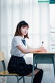 A woman sitting at a desk writing on a piece of paper.