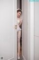 A woman in a white lingerie standing in a doorway.