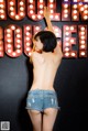 A woman standing in front of a neon sign that says "Joulin Rouge!"