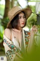 A woman in a straw hat holding a plant.