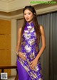 A woman in a purple and gold dress posing for a picture.