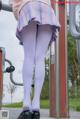 A woman in a pink sweater and purple skirt is standing on a playground.