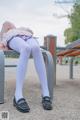 A woman sitting on a bench with her legs crossed.