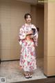 A woman in a kimono standing in a hallway holding a book.