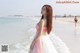 A woman standing on a beach next to the ocean.