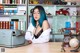 A woman with blue hair sitting at a desk in front of a typewriter.