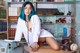 A woman with blue hair sitting at a desk in front of a bookcase.