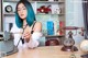 A woman with blue hair sitting at a desk in front of a typewriter.