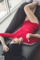 A woman in a red shirt laying on a couch.