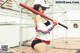 A woman in a baseball uniform holding a baseball bat.