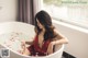 A woman in a red dress sitting in a bathtub filled with water.