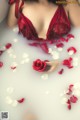 A woman in a bathtub with rose petals floating around her.