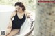 A woman in a black bathing suit sitting in a bathtub.