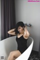 A woman in a black dress sitting in a bathtub.