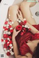 A woman in a red dress laying in a bathtub with rose petals.