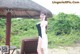 A woman in a black and white dress standing under a thatched umbrella.