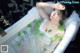 A woman laying in a bathtub covered in ivy leaves.