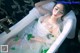 A woman in a white dress laying in a bathtub.