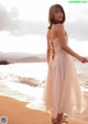 A woman in a white dress standing on a beach.