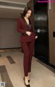 A woman in a red suit standing in an elevator.